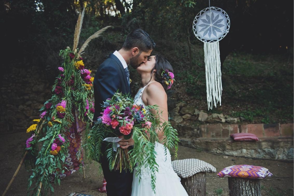 Novios besándose entre flores en boda boho de Cristina Perea