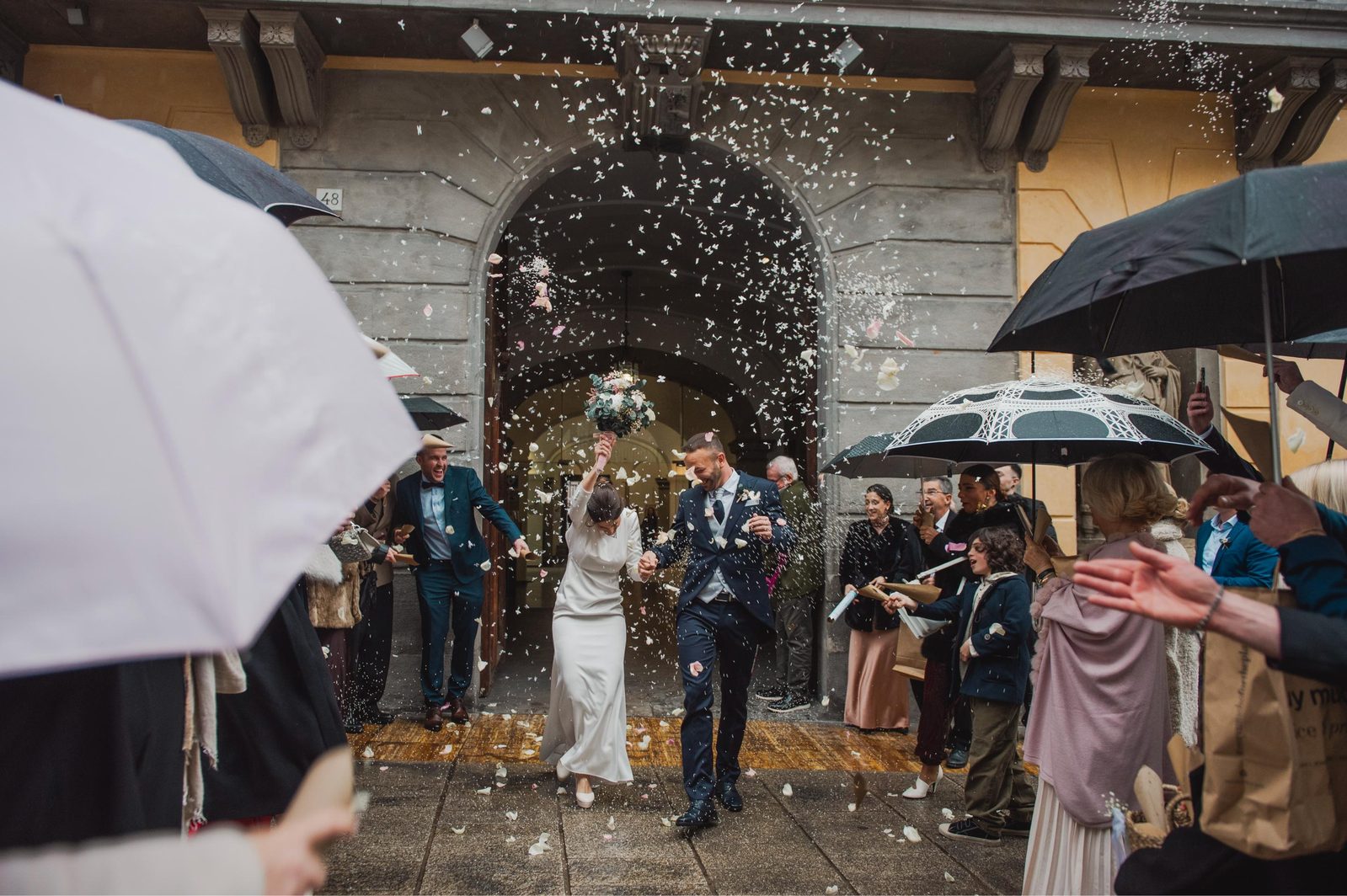 Novios bajo paraguas con confeti tras la ceremonia